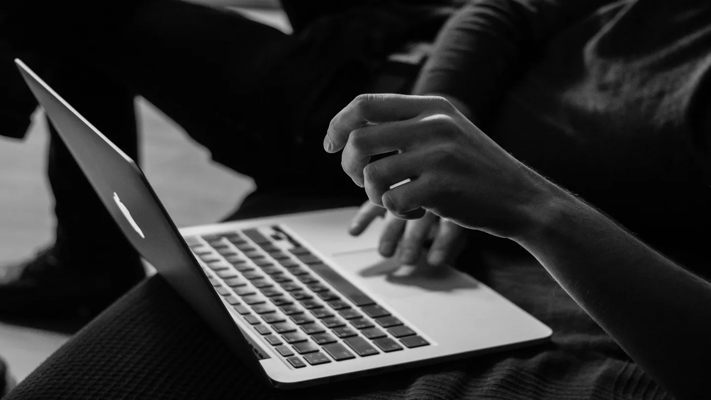 Person using a Mac laptop at a desk, representing long-form dictation workflows on macOS