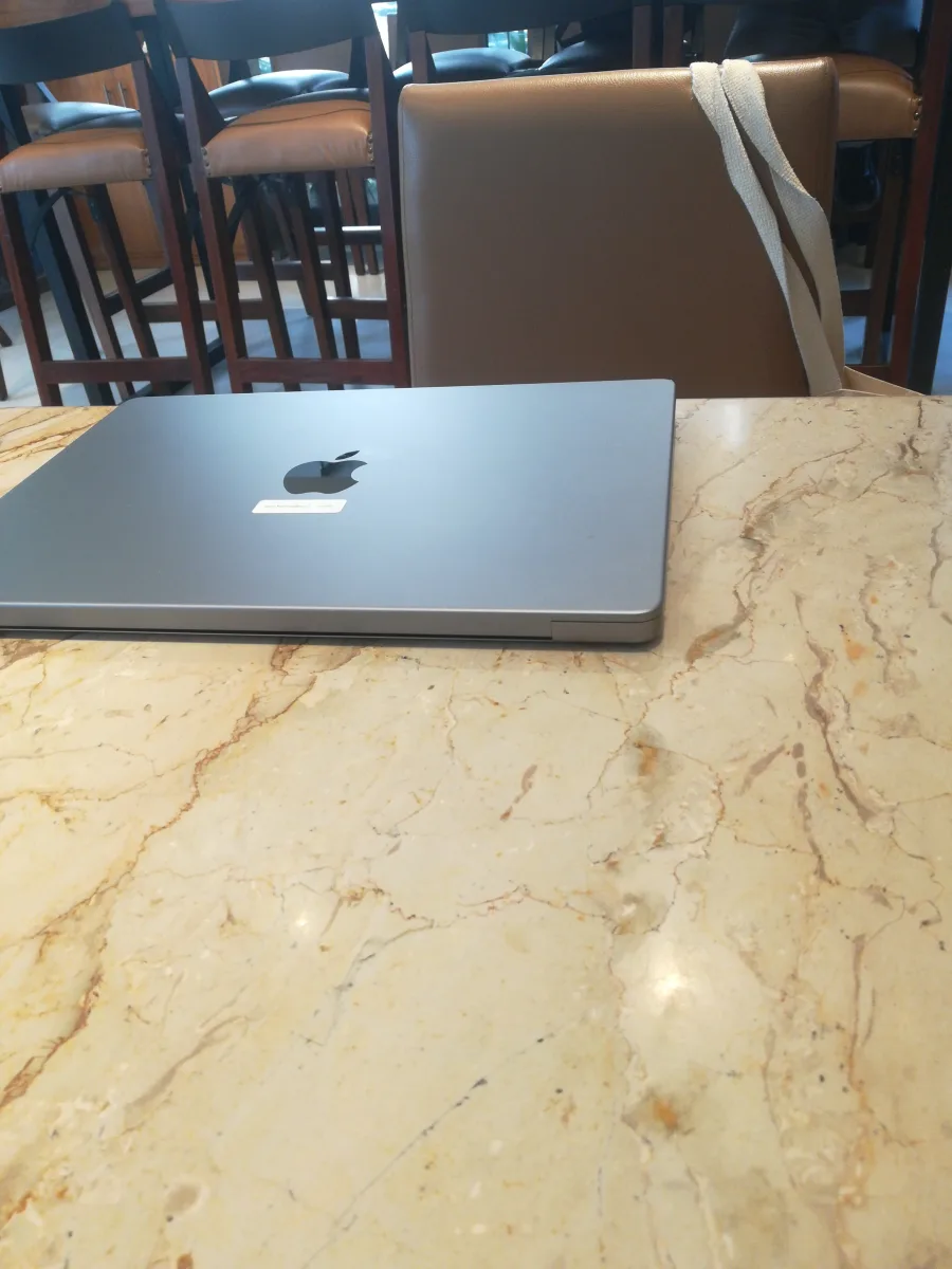 A closed Space Grey MacBook on a marble café table