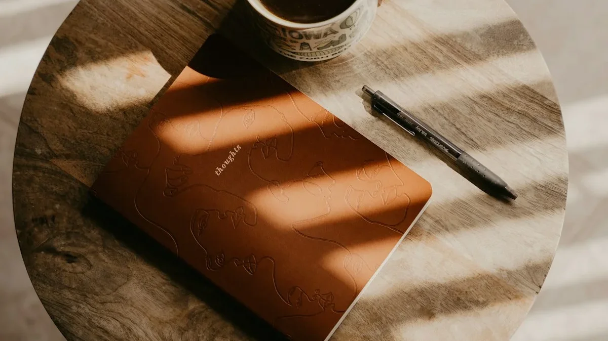 A leather journal, cup of coffee, and pen on a round wooden table with warm morning sunlight — a daily voice journaling setup